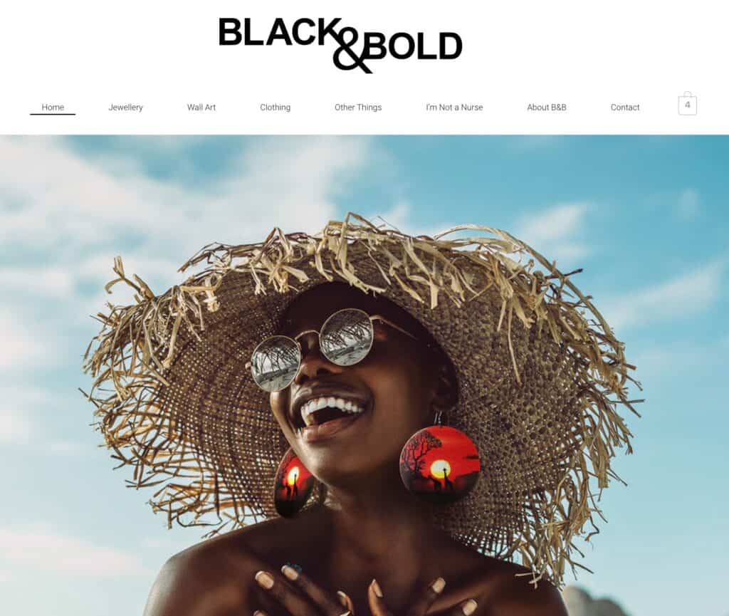 Woman wearing a large straw hat, sunglasses, and red earrings, smiling outdoors against a blue sky.