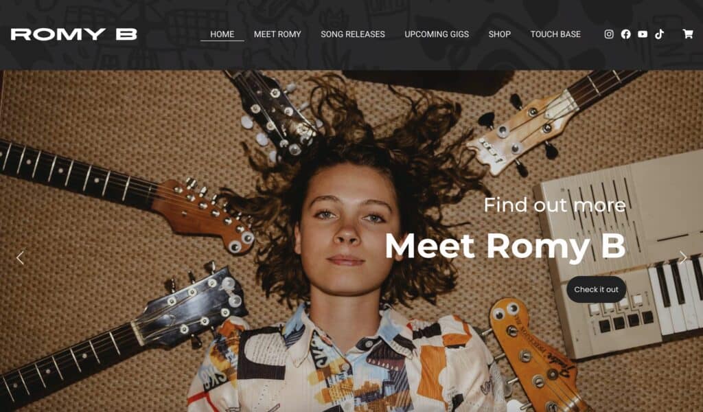 Portrait of Romy B with guitars and keyboard in background.